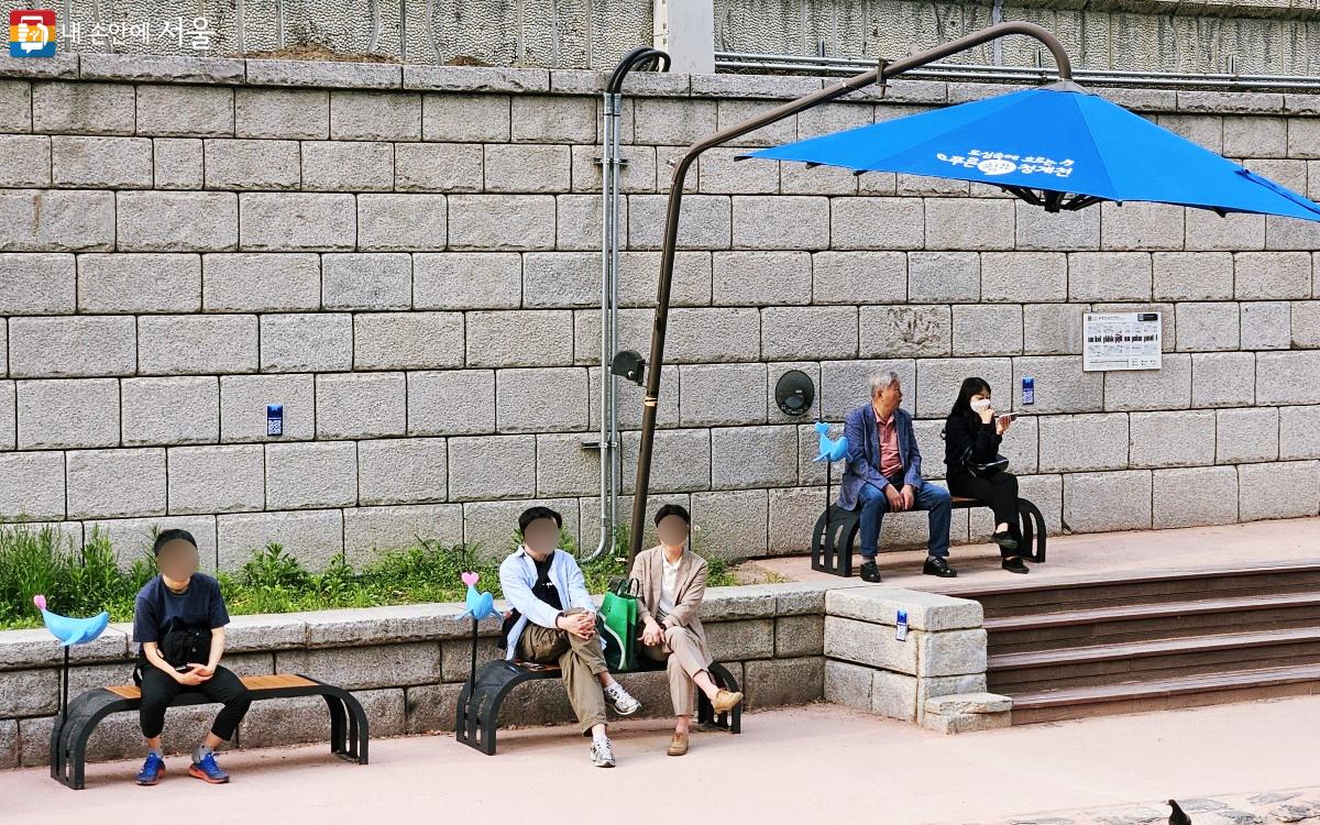 시민들이 고래 조형물이 장식된 벤치에 앉아서 쉬고 있다. ©송지혜