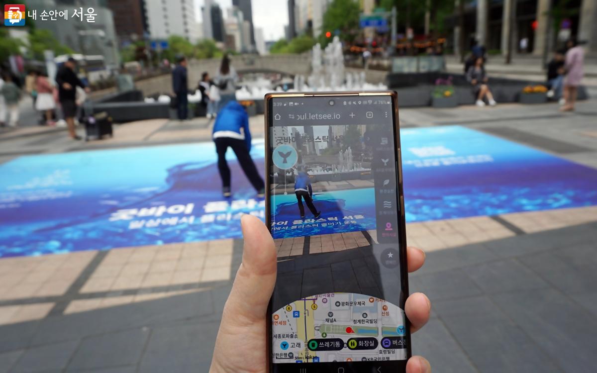 스마트폰을 이용해 청계천광장 바닥에 설치된 ‘슬픈 고래’ QR코드를 찍어보자. ⓒ김윤경