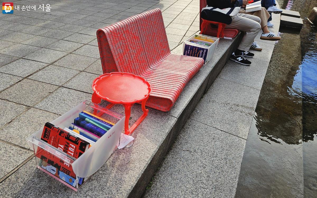 청계천 왼쪽에 붉은색 의자와 호족반, 책 바구니가 일렬로 놓여 있다. ©송지혜