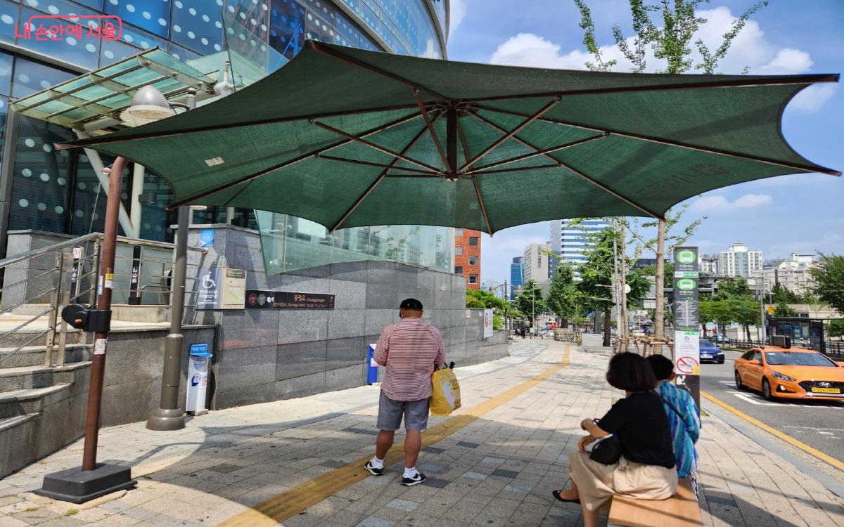 시민들이 횡단보도 앞 그늘막에서 녹색으로 신호가 바뀔 때까지 대기하고 있다. ⓒ윤혜숙