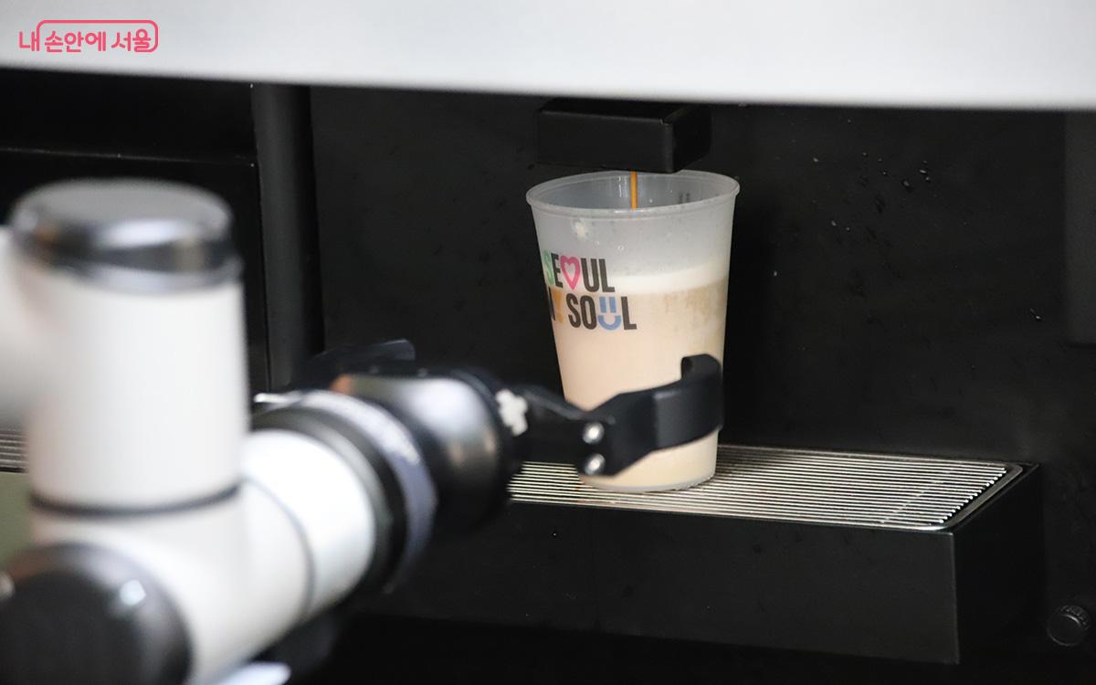 투명한 유리 벽 너머로 로봇 바리스타가 섬세한 동작으로 커피를 추출하고 있다. ©이혜숙