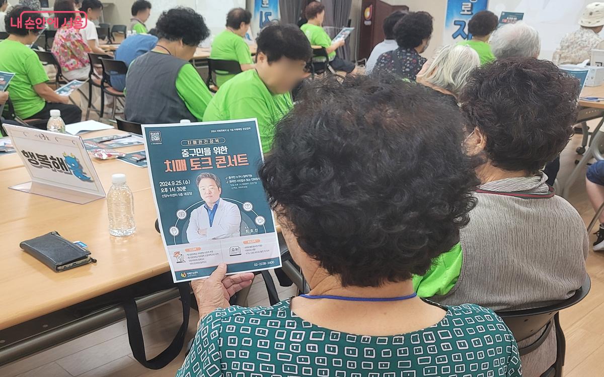 한 어르신이 치매 극복 토크 콘서트 유인물을 보고 있다. ⓒ김윤경