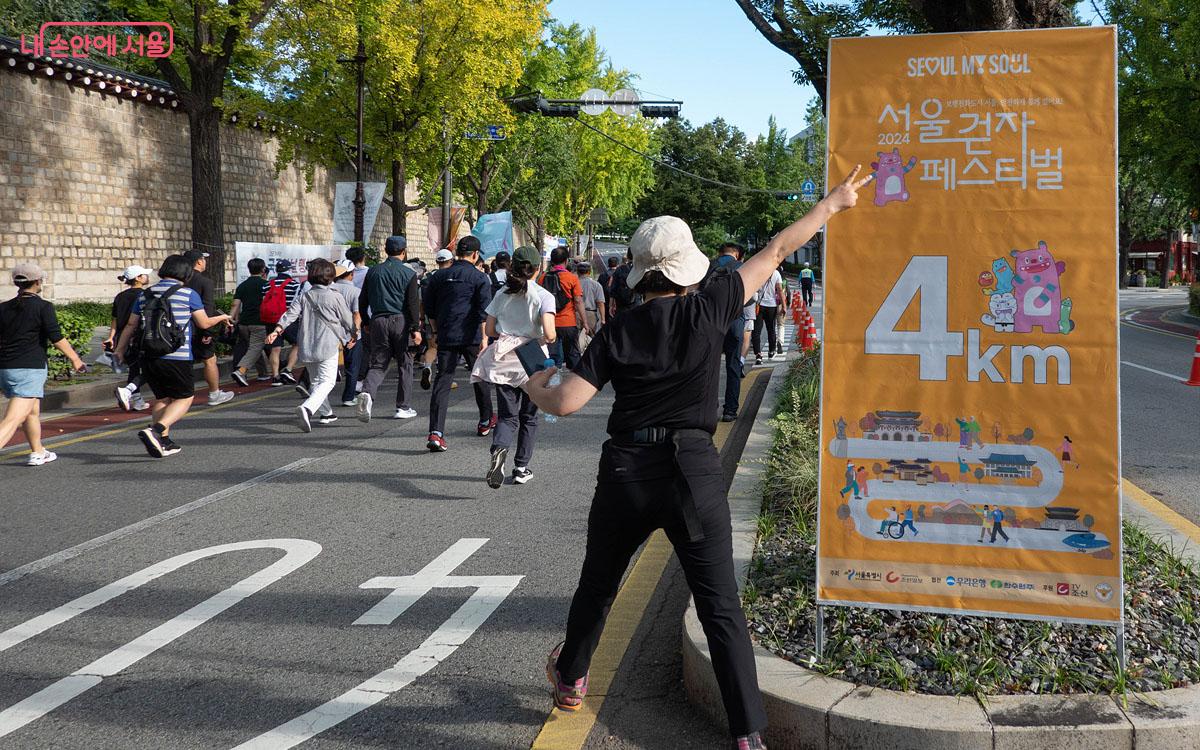 걷자 코스 6Km 중 4km 지점에 준비한 경과 게시판 앞에서 참여자가 포즈를 취하고 있다. ©김인수