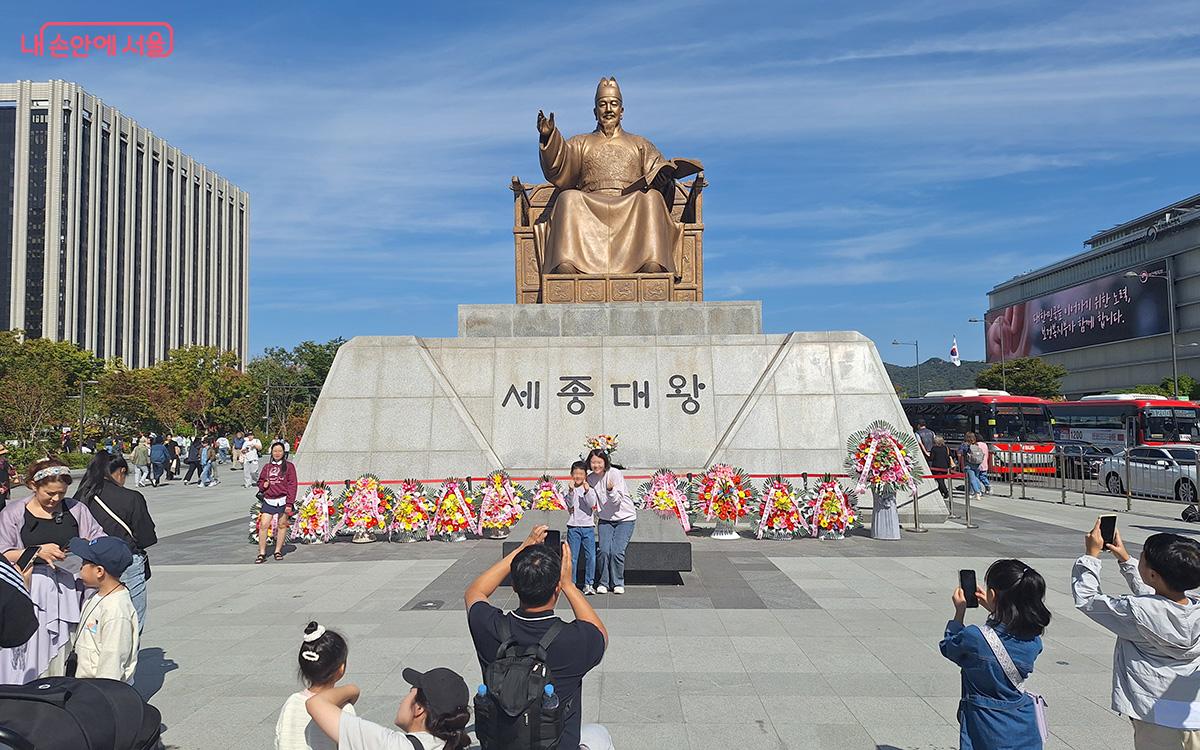 세종대왕 동상 앞에서 활짝 웃으며 기념 사진을 찍는 엄마와 어린이의 모습이 정답다.