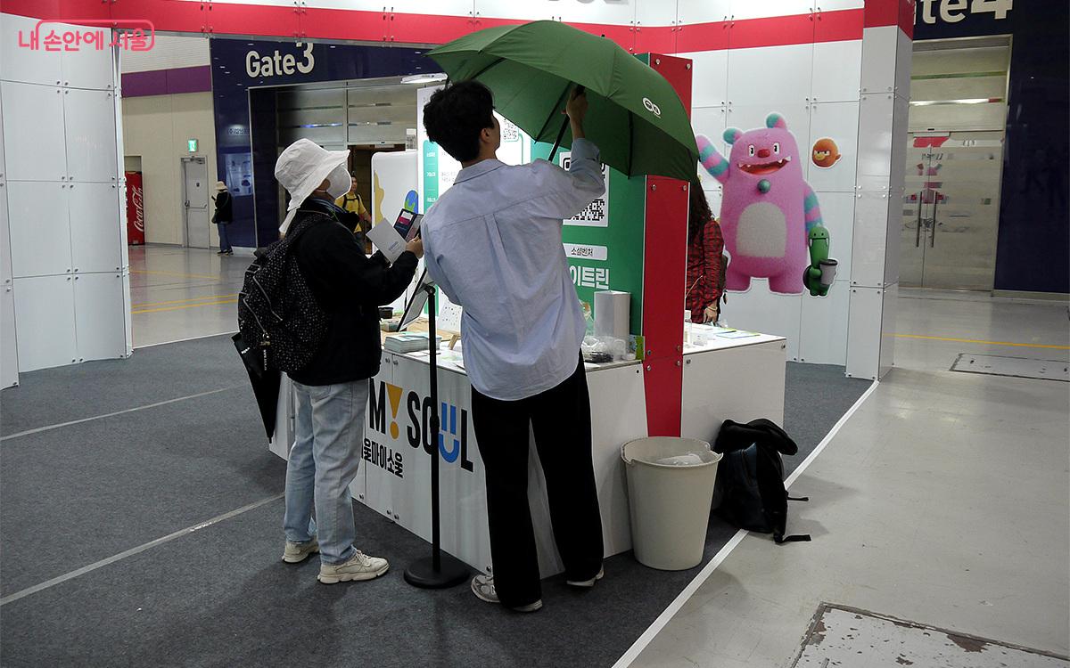 A visitor is looking at ‘Aitrine’ umbrellas made from upcycled waste plastic. ©Choi Yunyoung