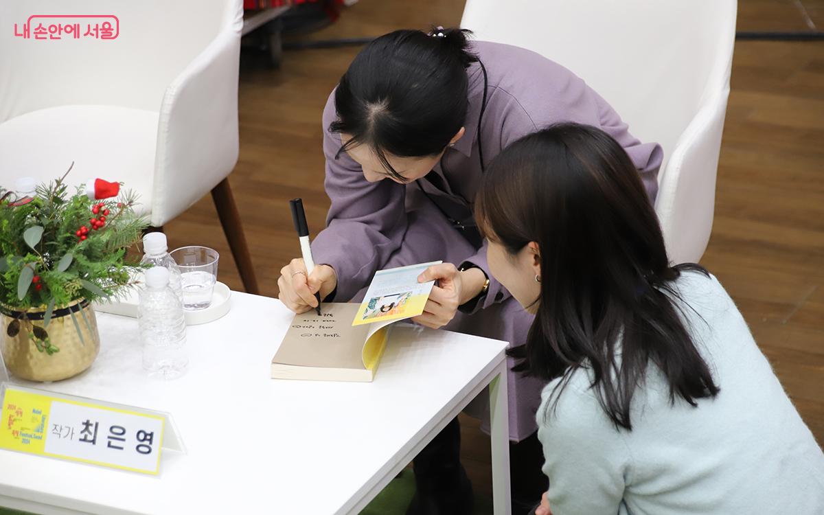 최은영 작가가 자신의 소설 <아주 희미한 빛으로도> 표지에 사인을 해주고 있다. ©이혜숙