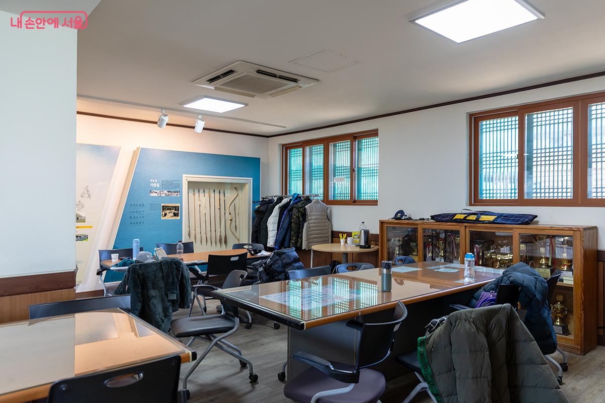 석호정 내부 공간에 여러 개의 책상과 의자, 전시된 활과 화살, 트로피 및 상패들이 배치된 모습 ©문청야