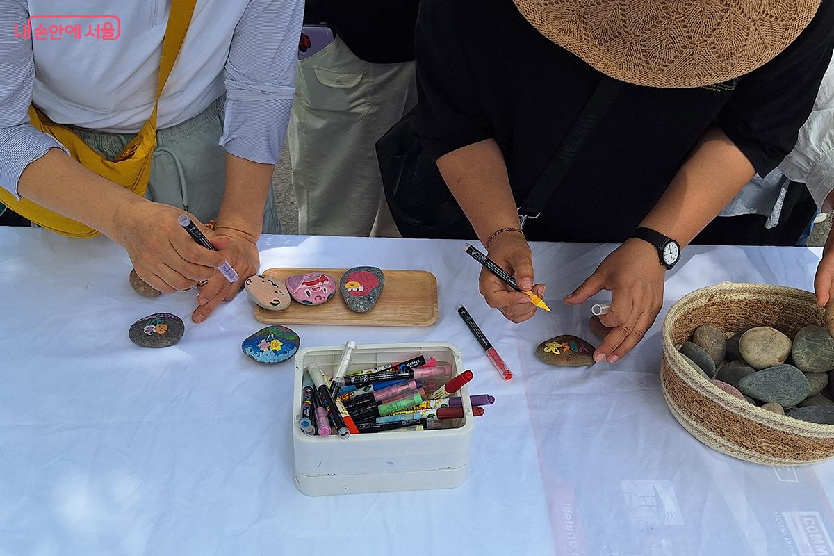 관람객들이 '여행하는 돌' 부스에서 나만의 조약돌 만들기를 체험하고 있다. ©정향선