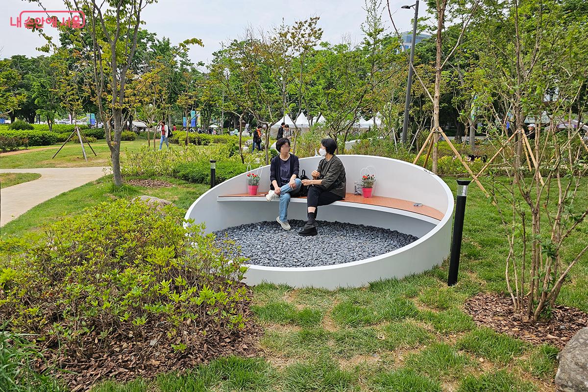  따뜻한 햇살 아래 놓인 멋진 벤치에 두 여인이 다정하게 담소하는 모습 ©정향선