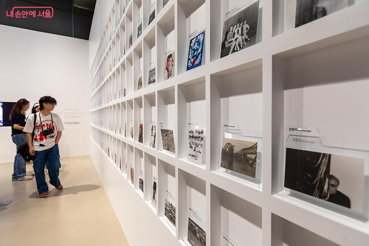 관람객들이 벽면을 가득 채운 사진들을 유심히 보고 있다. ©문청야