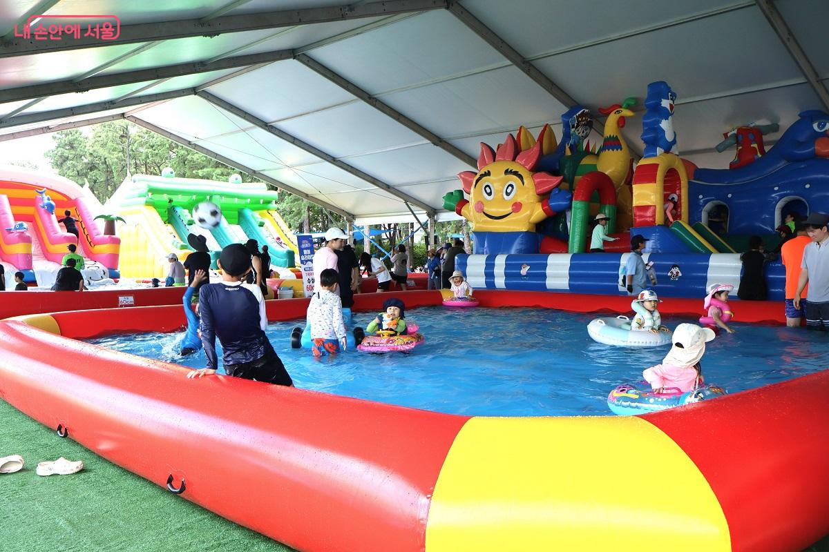 어린이들이 구명조끼를 입고 영유아 풀장에서 안전하게 놀고 있다.