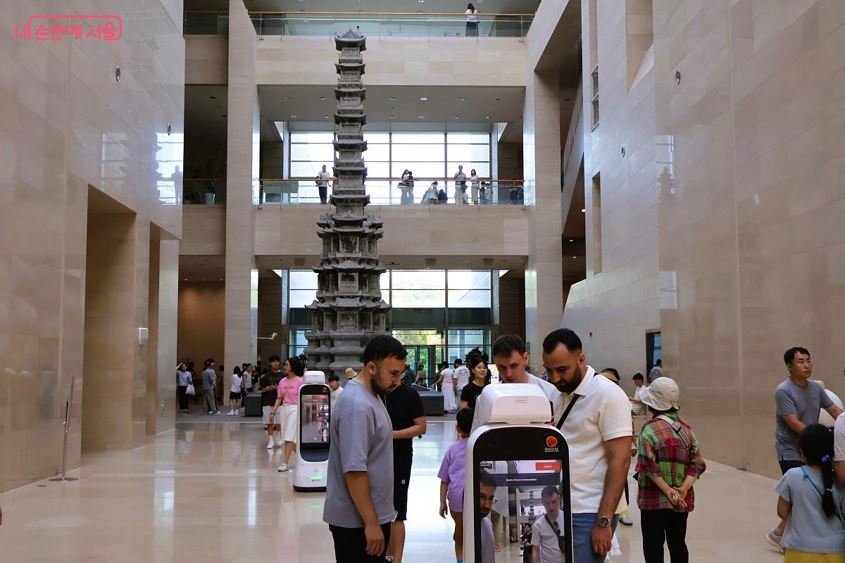 외국인 방문객들이 전시관 안내 로봇을 신기하게 바라보며 사용법을 알아보고 있다. ©이봉덕