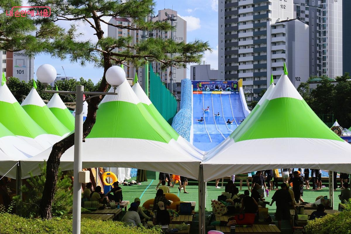 아이들은 물놀이 하고 어른들은 평상 쉼터에 앉아 구경하며 즐거운 여가를 보내고 있다.