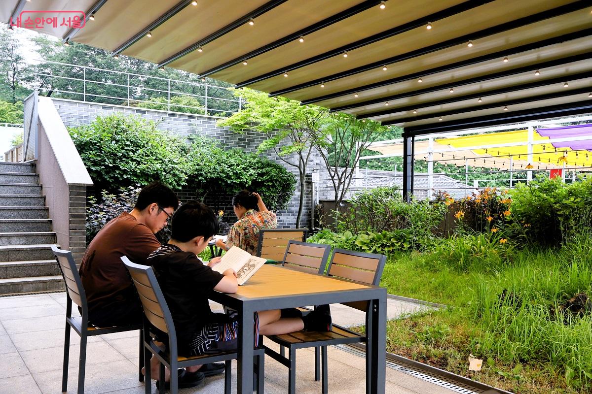 야외 테라스 정원에 옹기종기 앉아서 선선한 바람을 맞으며 책 읽는 가족들 ©이봉덕