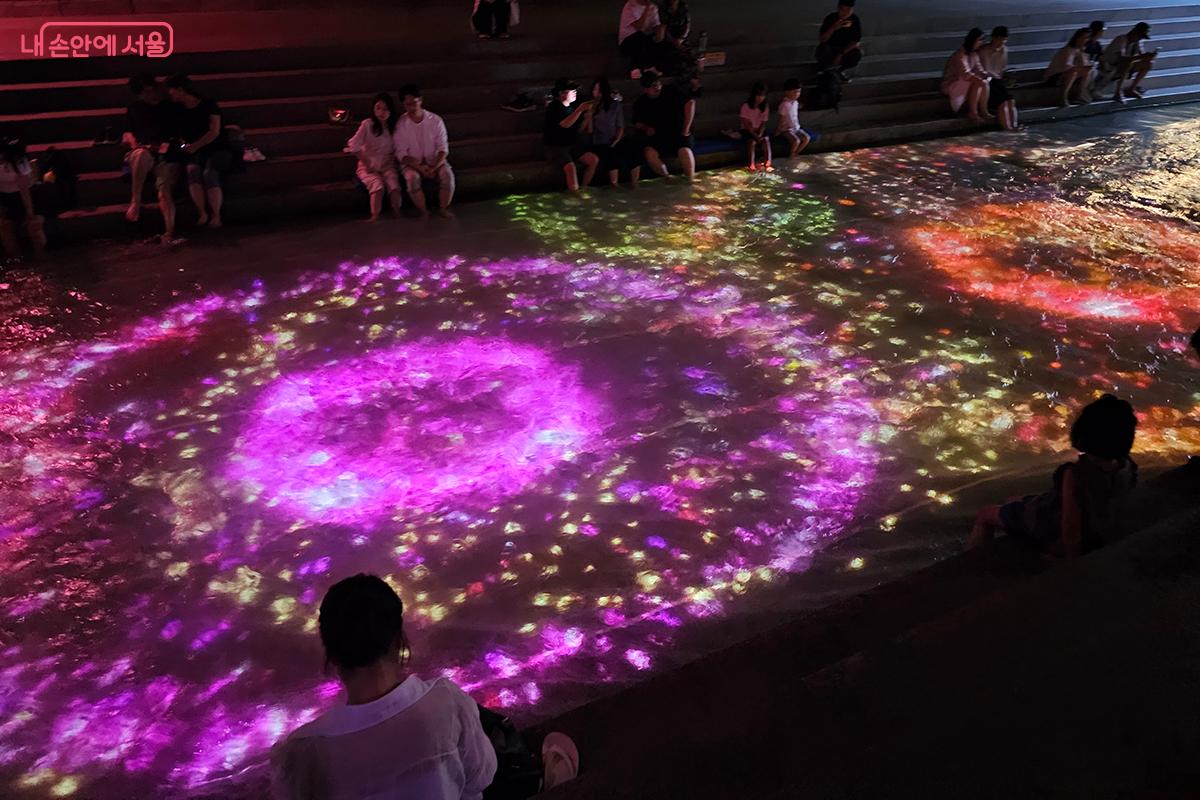 청계천 물결 위에 마치 꽃이 핀 듯, 보라색, 주황색의 화려한 색상이 만들어내는 영상이 시민들의 감탄을 자아낸다. ©정향선