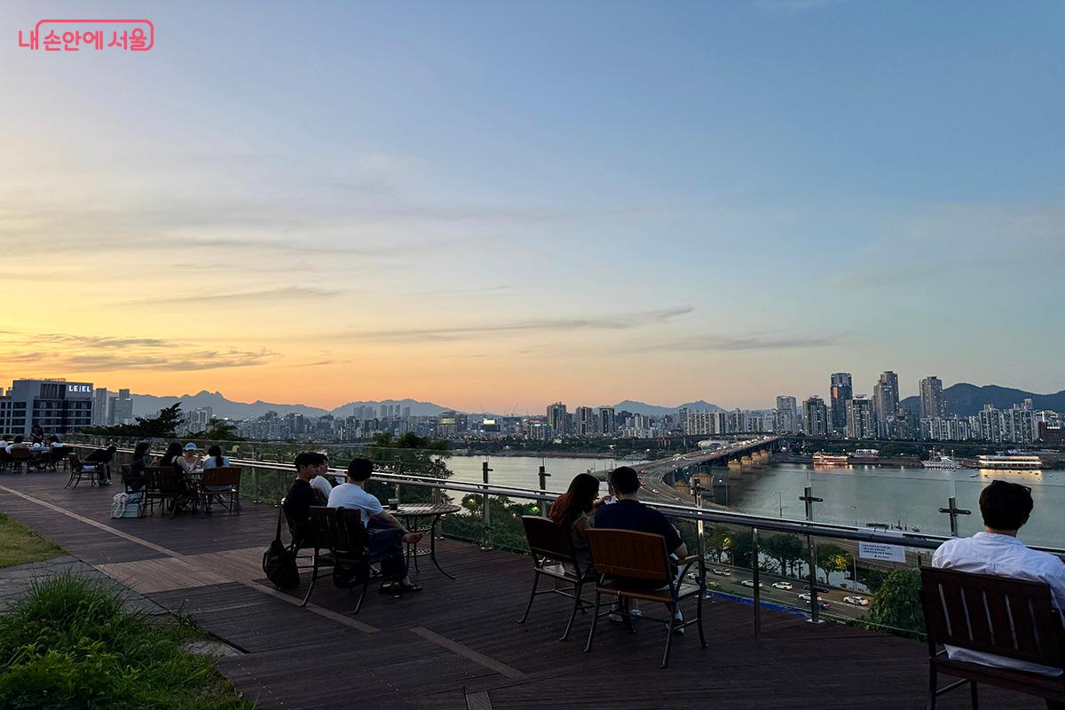 벤치에 앉아 한강 노을을 바라보는 사람들의 모습이 여유롭다. ©김미정