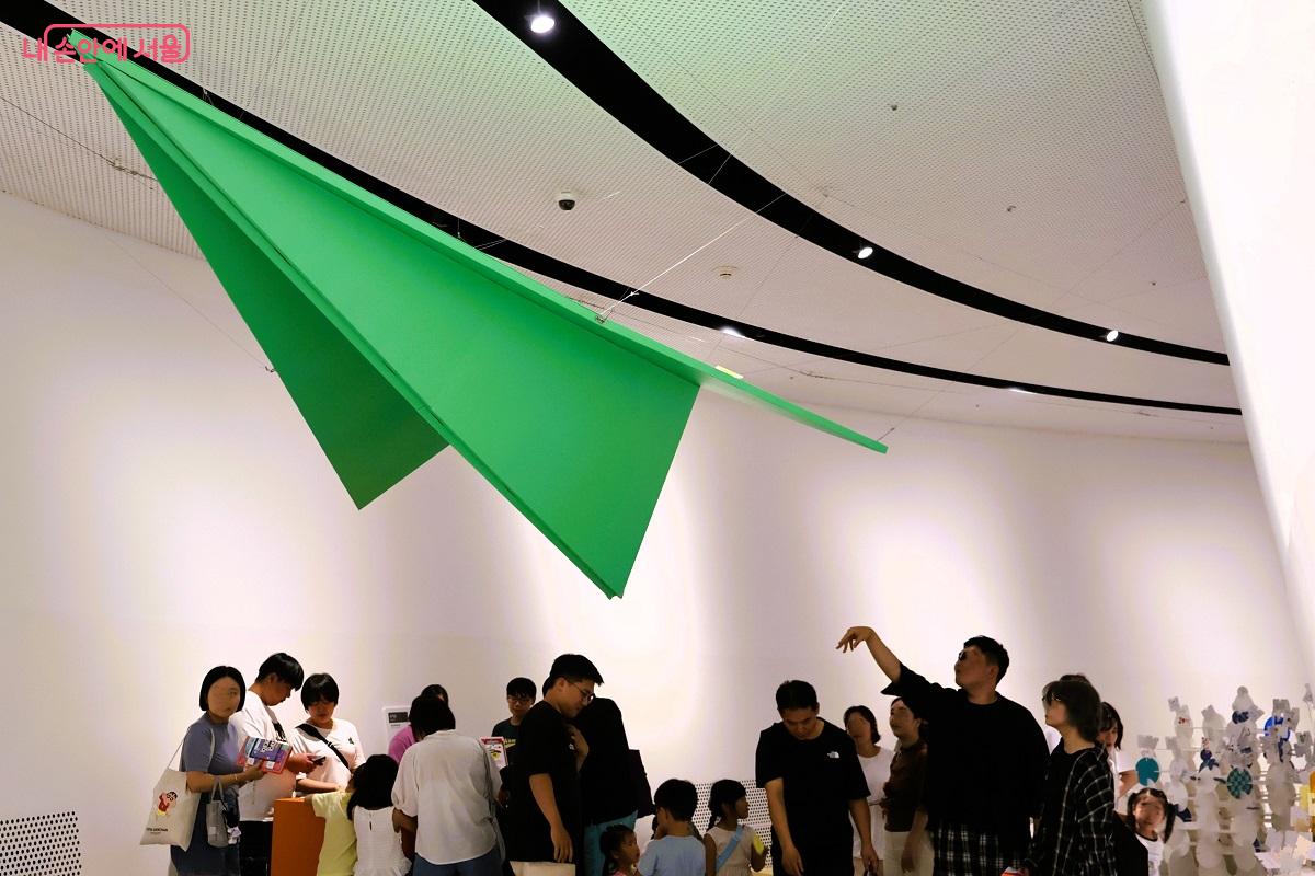 온 가족이 함께 종이비행기 게임에 즐겁게 참여하고 있다. ©이봉덕