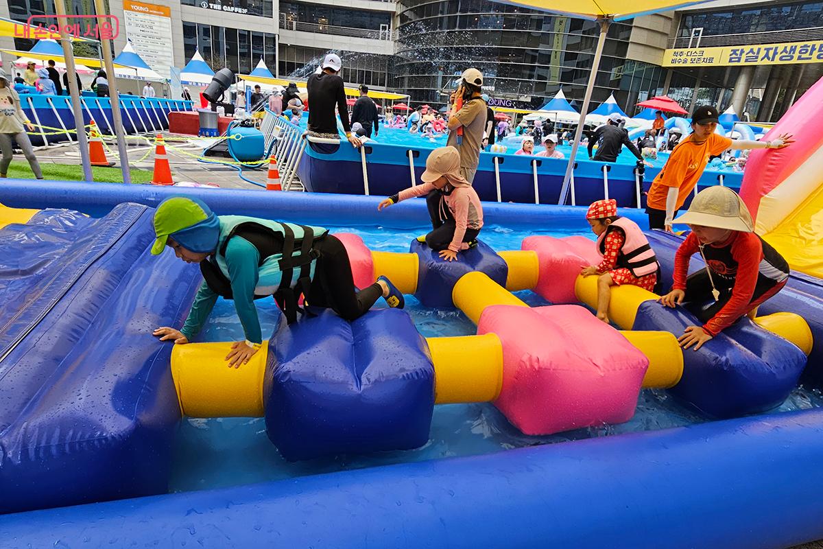 아이들이 물에 빠지지 않게 조심하며 구름다리 코스를 엉금엉금 기어 열심히 통과하고 있다. &copy;이혜숙