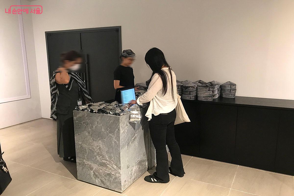 퍼포먼스 관람 전 카자흐스탄의 전통 모자와 반짝이는 비닐을 받고 관람객의 이름을 적는다. ©이정민