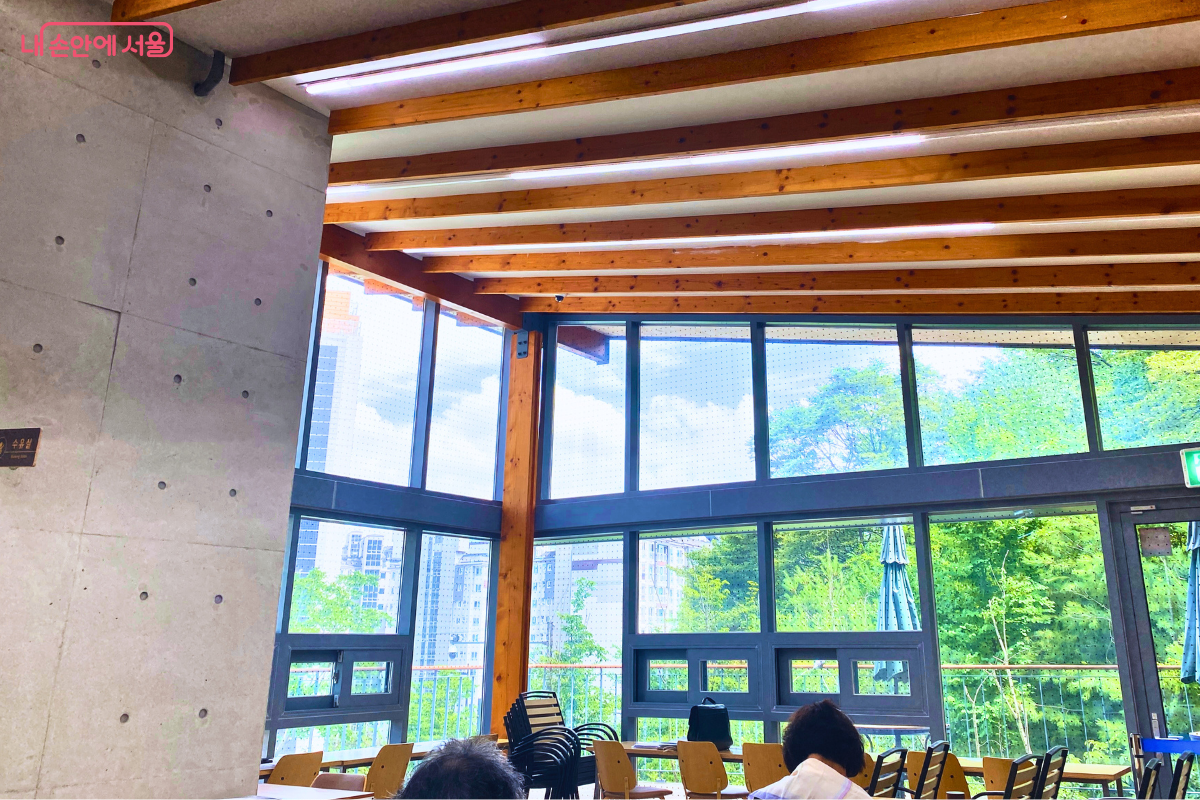 큰 유리창 너머 숲과 도시 풍경이 보이는 매봉산숲속도서관 열람실 ©양정화