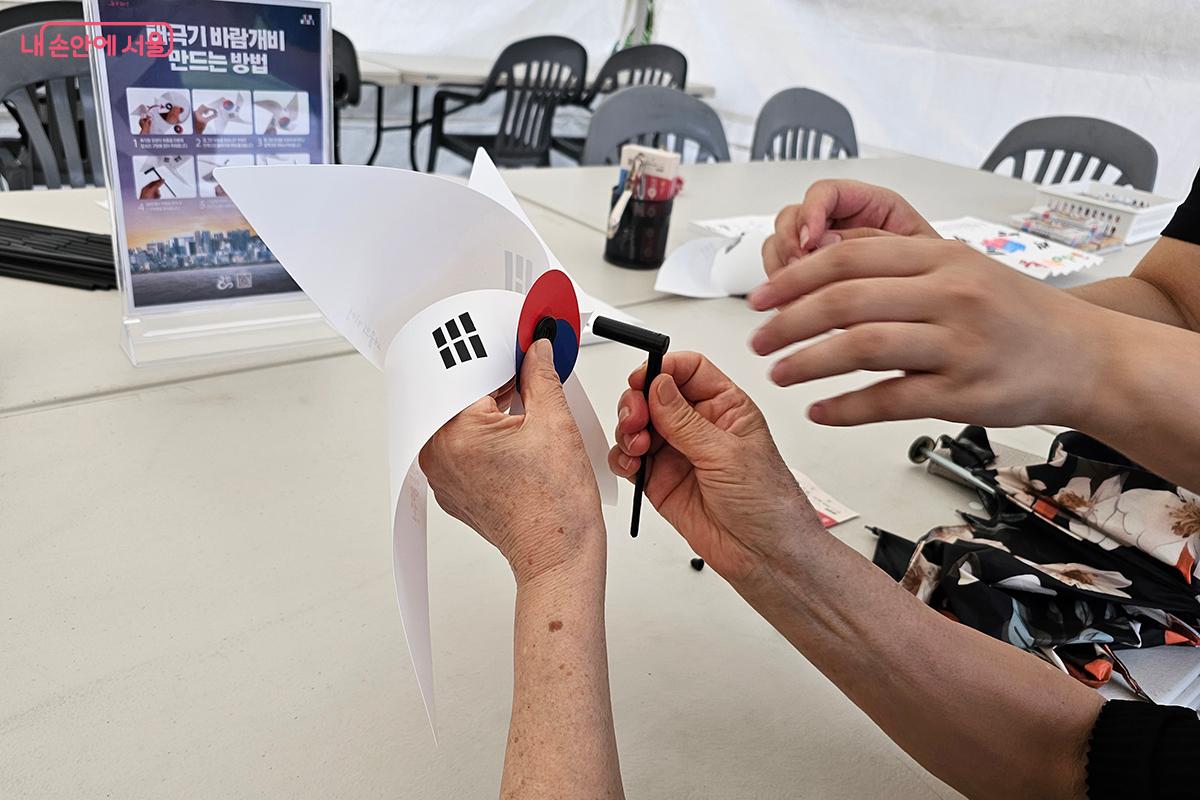 태극기 문양을 오리고 풀로 붙인 후 가운데 홈에 바람개비 막대를 꽂으면 나만의 광복절 바람개비가 완성된다. ©정향선