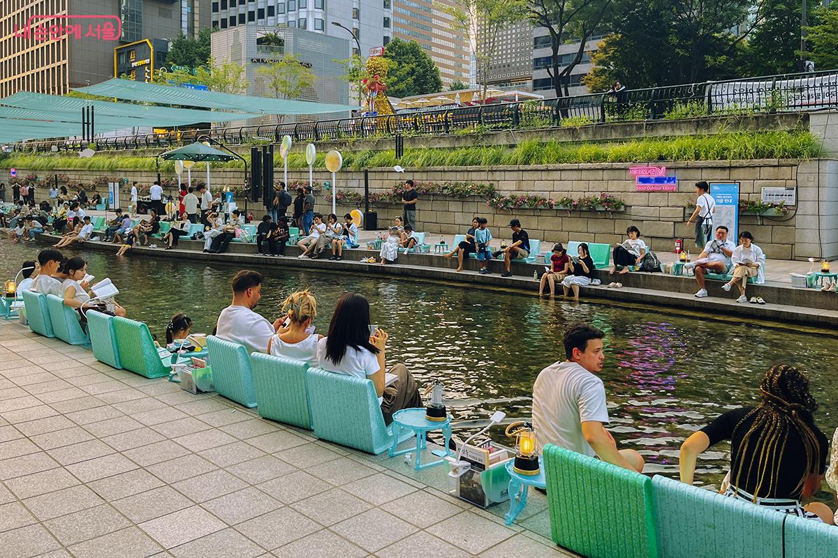 청계천에 발을 담그고 시원한 여름 오후 독서를 즐기는 사람들 ©김아름