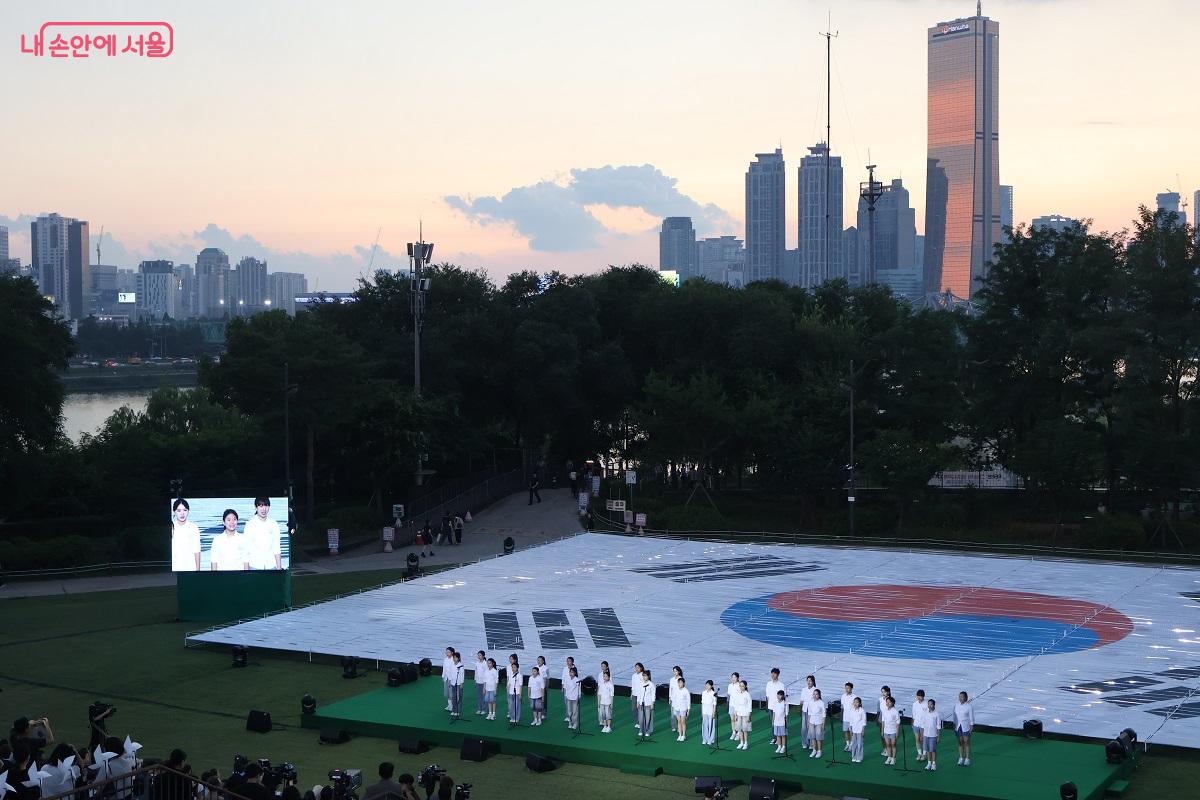 '광복의 바람'을 형상화한 가로 40m, 세로 27m 초대형 태극기 작품이 설치된 잔디마당에서 광복 80주년 기념 행사가 열렸다. 첫 순서로 진행된 서울시소년소녀합창단 합창 공연 ©이봉덕