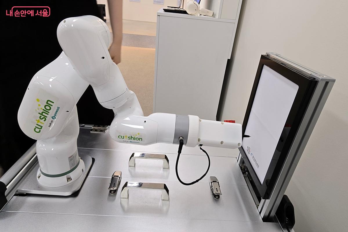 로봇이 앉아 있는 사람의 얼굴을 그리고 있다. ©김윤경