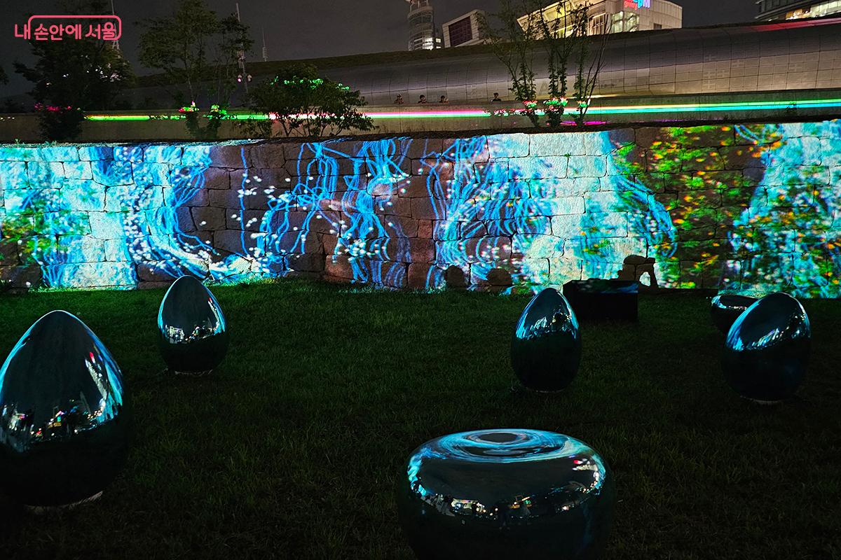 'Fluid Memory' 는 프로젝션 맵핑 기법을 통해 한양도성 성곽의 결을 따라 유영하는 빛의 물결을 보여준다.