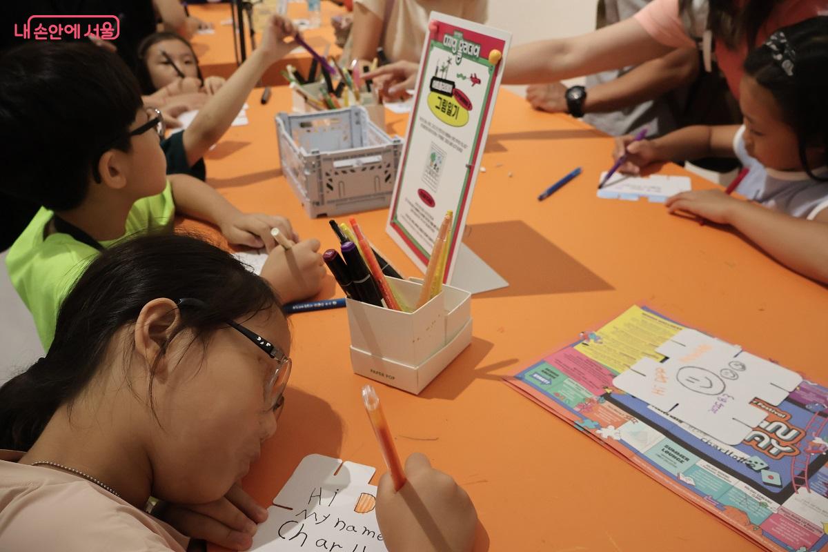 어린이들이 함께 모여 그림과 글로 소원을 그리며 쓰고 있다. ©이봉덕   