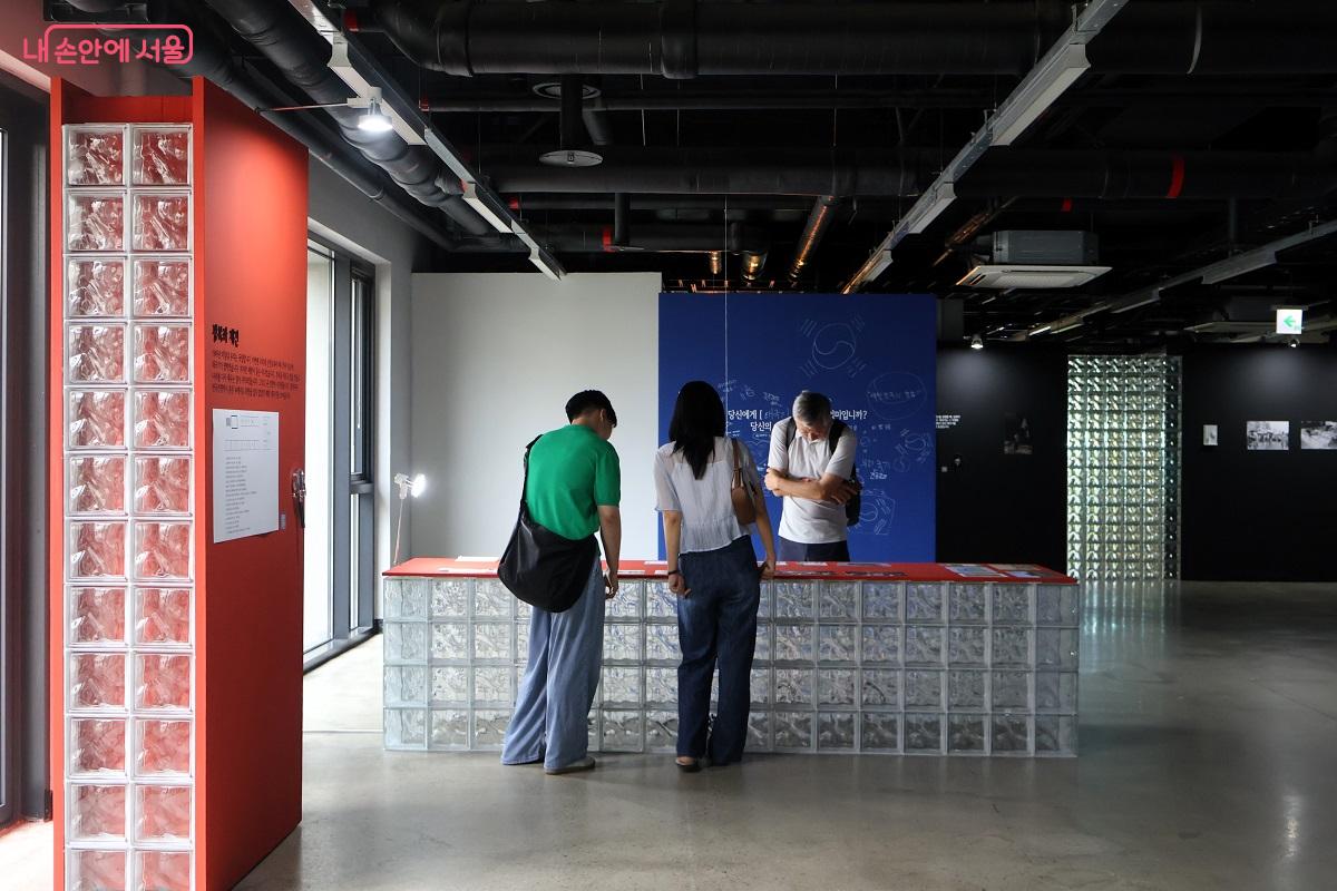 태극기와 함께 한 한국 근현대 속 주요 순간이 담긴 사진을 찬찬히 살펴보고 있는 관람객들 ©이봉덕