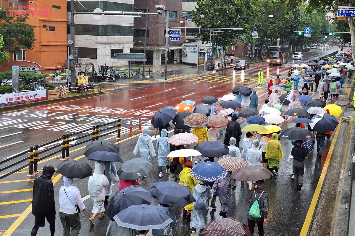 시민들이 흥인지문 언덕을 지나 이화사거리와 원남동 사거리로 이어지는 도로 위를 걸어가고 있다.