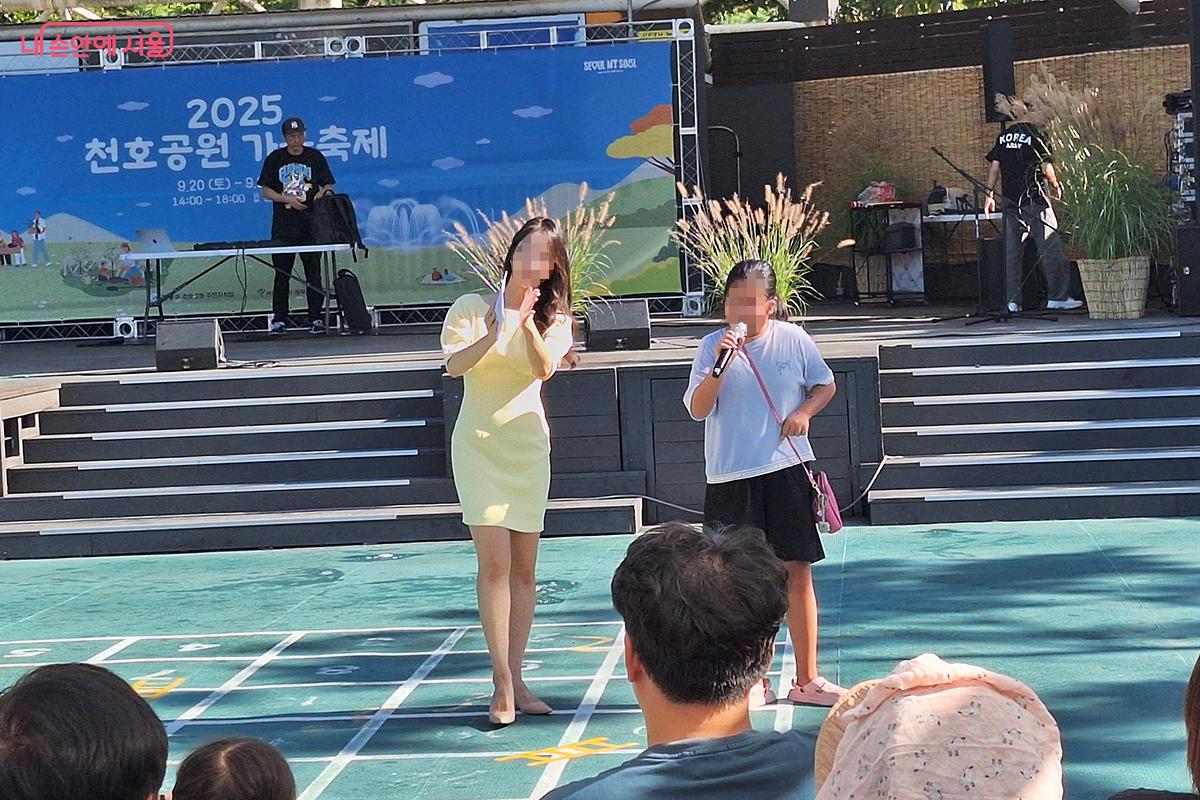 '노래자랑' 에 참가한 어린이가 관객들의 박수에 맞춰 노래를 부르며 자신의 장기를 뽐내고 있다.