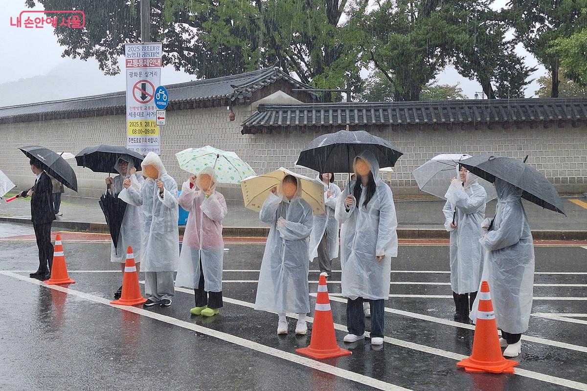 우비를 입은 서울체대 응원단이 비를 맞으며 걷기 페스티벌에 참여한 참가자들을 응원하고 격려의 구호를 외쳐주고 있다.