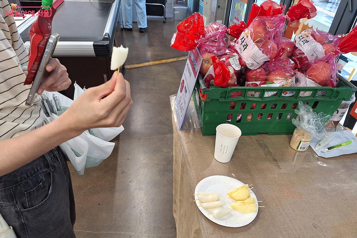 '서울동행상회'를 찾은 소비자가 할인 판매되는 사과를 맛보고 있다. ©백승훈