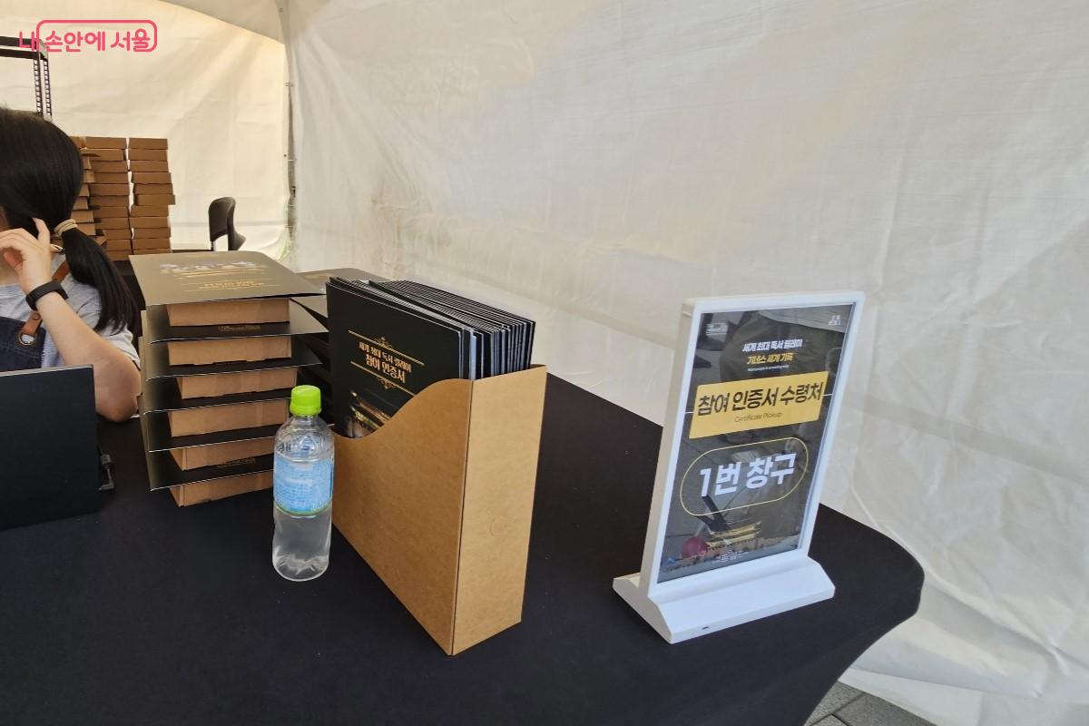 참여 인증서와 기프트 박스가 놓여져 있는 수령처 안 책상 ©최정윤