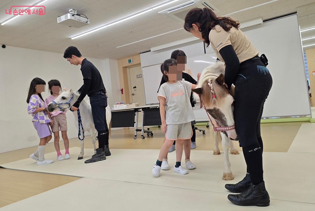 승마지도사의 도움을 받아 수줍게 말과 교감을 시작한 아이들 ©조성희