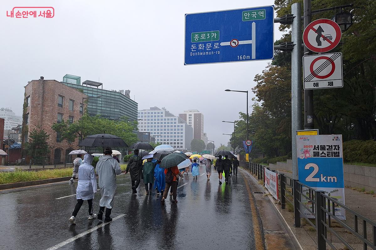 참가자들이 '2025 서울 걷자 페스티벌' 2km 지점을 알리는 표지판 앞을 통과하고 있다. 