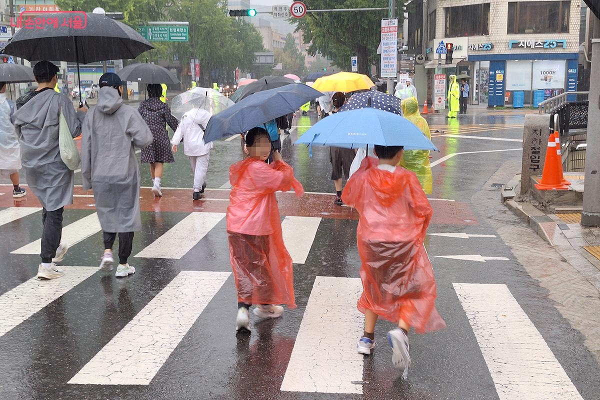빨간색 우의를 입고 씩씩하게 걸어가는 어린 형제의 모습이 보는 이의 미소를 자아낸다. 