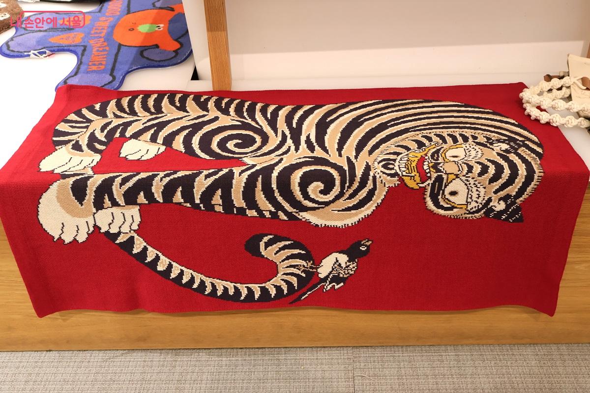 강렬한 붉은색 바탕 위에 호랑이와 까치가 선명하게 드러나며, 공간을 화려하게 채우고 있다. ©이봉덕