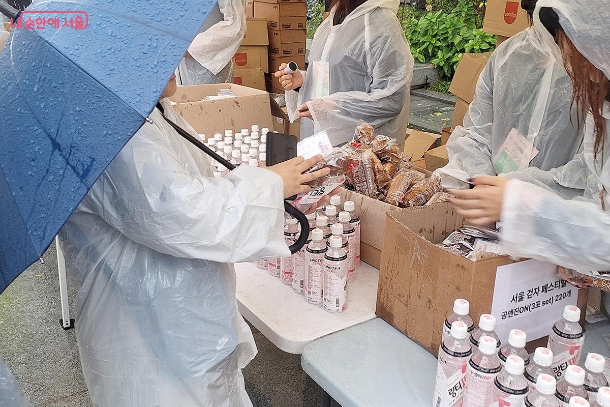 완주 후에 모바일 참가증을 보여주고 준비된 음료수과 다과, 기념품을 받는 참가자들의 모습