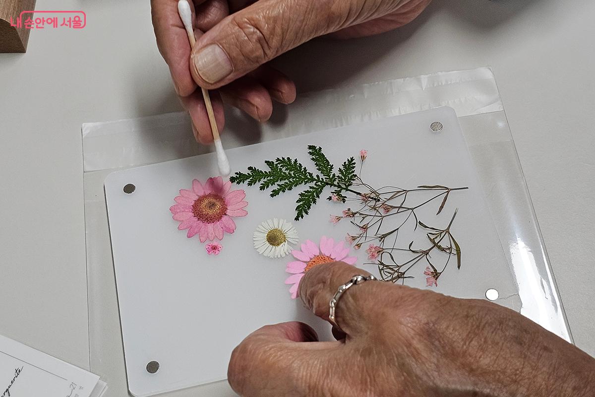 꽃 스티커를 아름답게 배치해 투명 액자 속에 생명을 불어넣는다. ©이혜숙