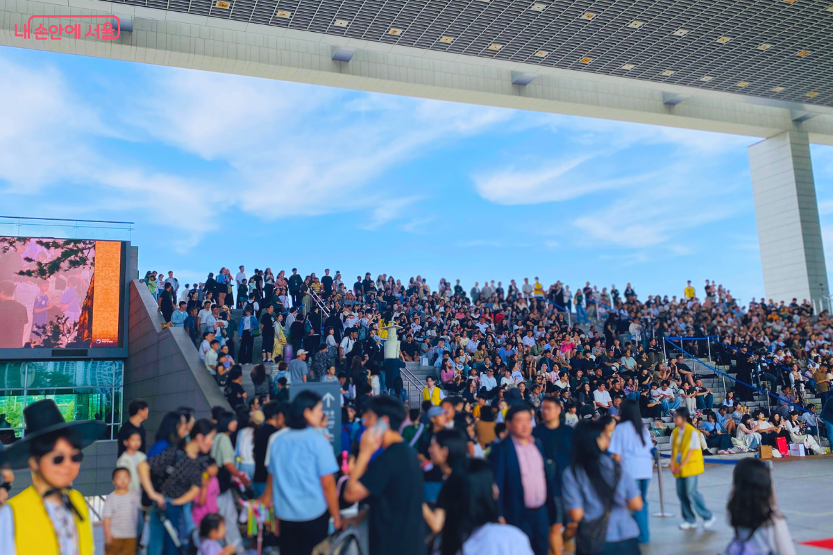 국립중앙박물관 열린마당 계단에 '국중박 분장대회' 시상식을 보기 위해 수많은 시민 관람객이 빽빽하게 앉아 있다. 맑은 하늘 아래, 모두 무대를 집중해서 바라보고 있다. ©양정화