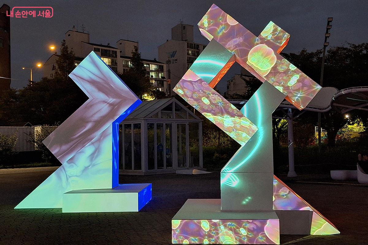 경희대학교 미술대학 조소 대학의 작품 '빛의 탑'은 아연 파이프와 미송 합판 위에 다양한 영상 효과를 표현한다.