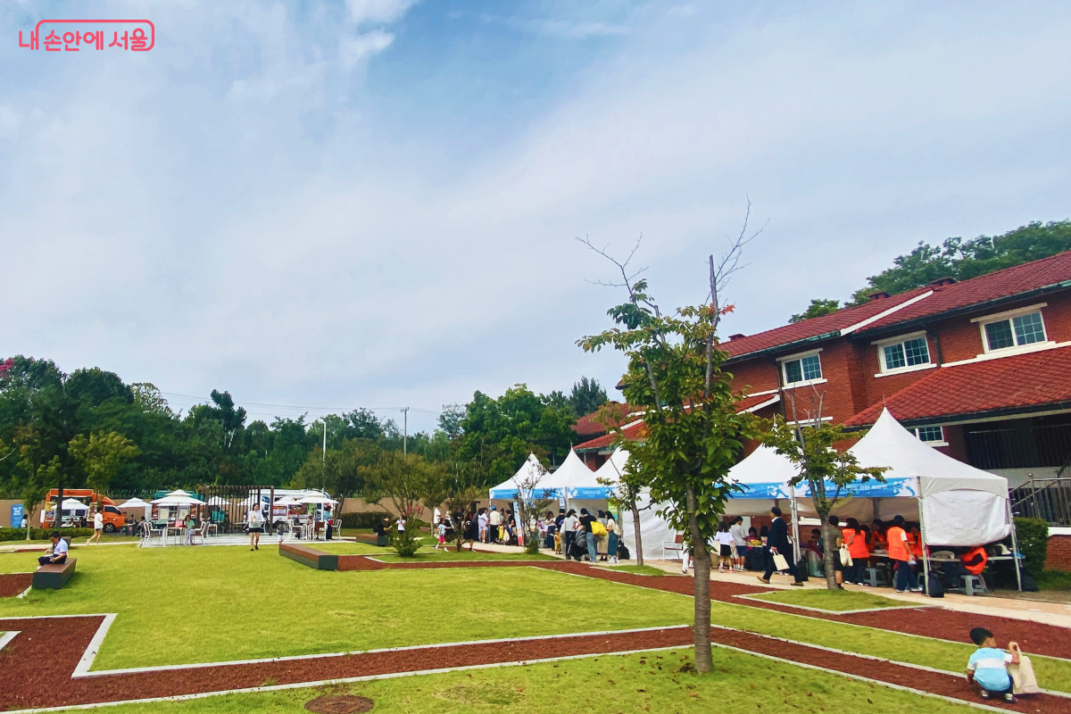 맑은 가을 하늘 아래 펼쳐진 축제장 전경. 넓은 잔디밭과 산책로를 따라 체험 부스들이 자리하고 있으며, 많은 시민이 여유롭게 축제를 즐기고 있다. ©양정화