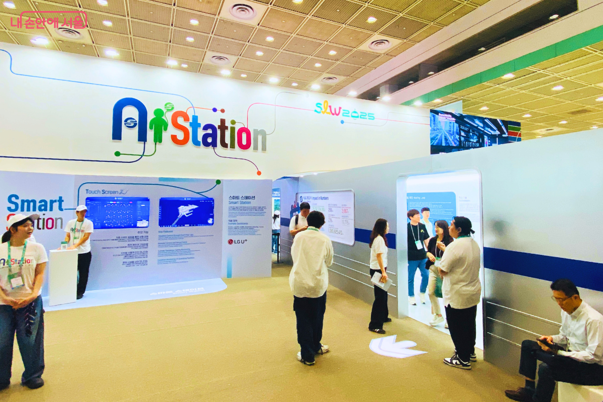 서울교통공사가 운영하는 'AI Station' 부스의 전경. 미래 지하철의 모습을 구현한 공간으로, 시민들이 스마트 스크린을 조작해보거나 전시된 미래형 게이트를 살펴보는 등 다양한 AI 기반 교통 및 안전 기술을 체험하고 있다.