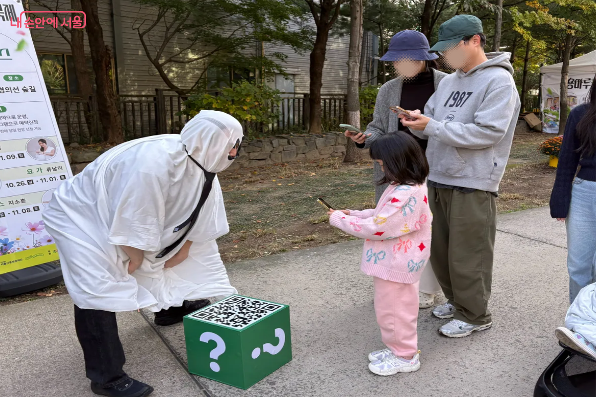 '물음표맨'의 QR을 스캔하며 즐거워하는 가족 ⓒ이혜린
