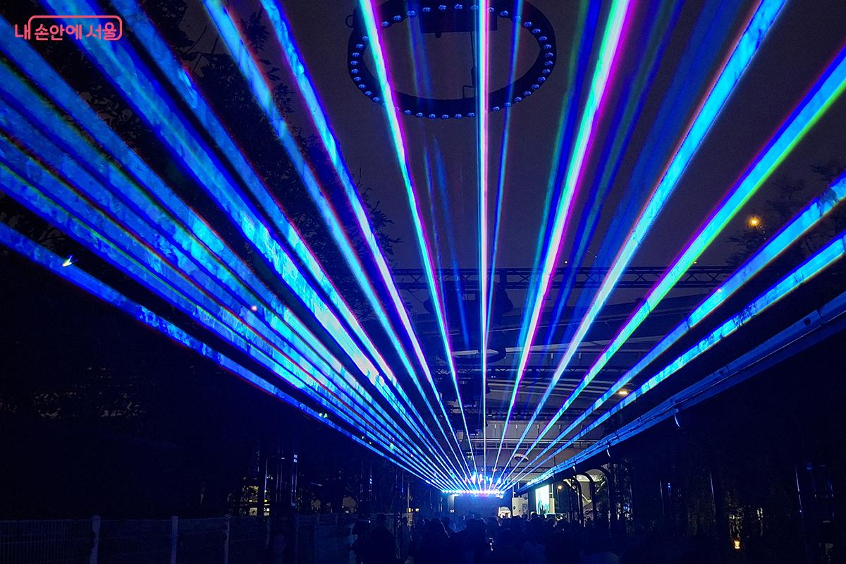 이 작품은 직선 레이저와 키네틱 서클 조명으로 도시의 에너지와 한강의 물결을 시각화했다.