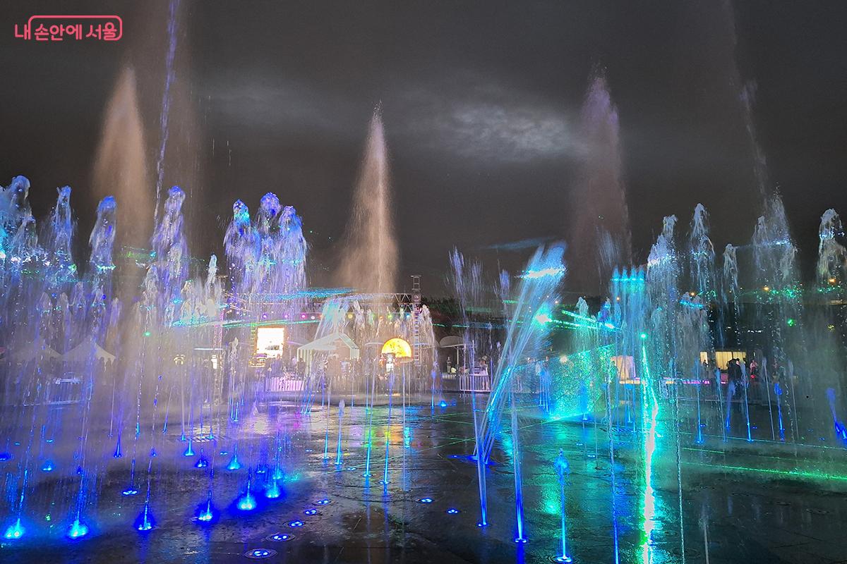 <소닉 오로라 > 작품은 4개의 탑에서 나오는 직선 레이저와 키네틱 서클 조명이 높이 솟아오르는 분수와 함께 황홀한 광경을 만들어낸다.