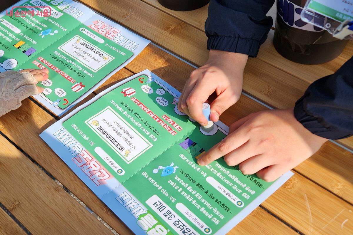 산책로 중간에 마련된 부스에서 직원이 미션에 성공한 참가자에게 스탬프를 찍어주고 있다.ⓒ윤혜숙